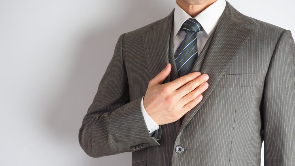 スーツ姿の男性が胸に手を当てて立っている。誠実さを示す画像。