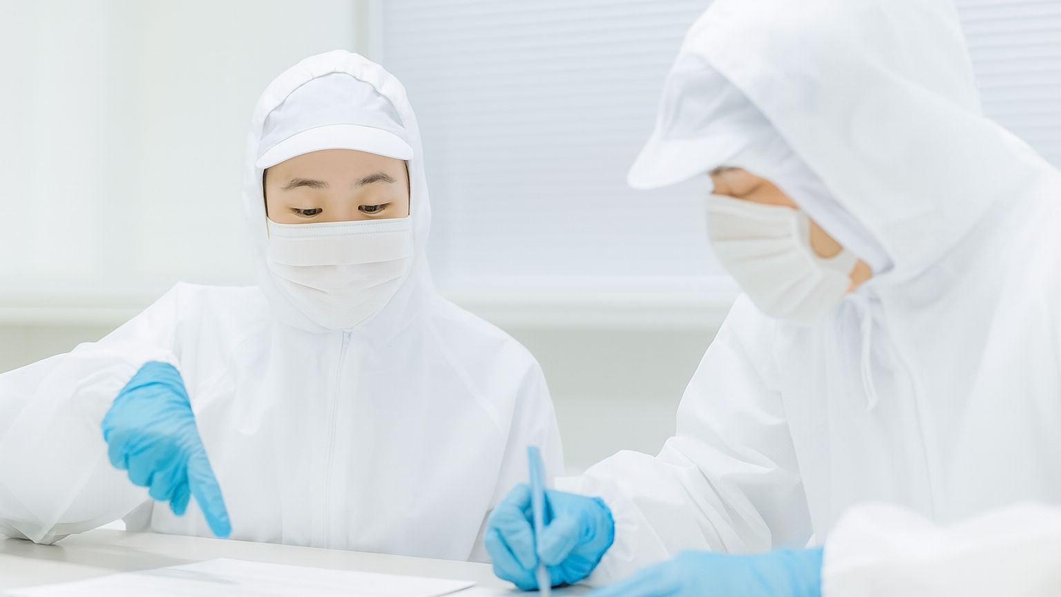 白衣の男女が品質検査を行っている。高品質を象徴する画像。